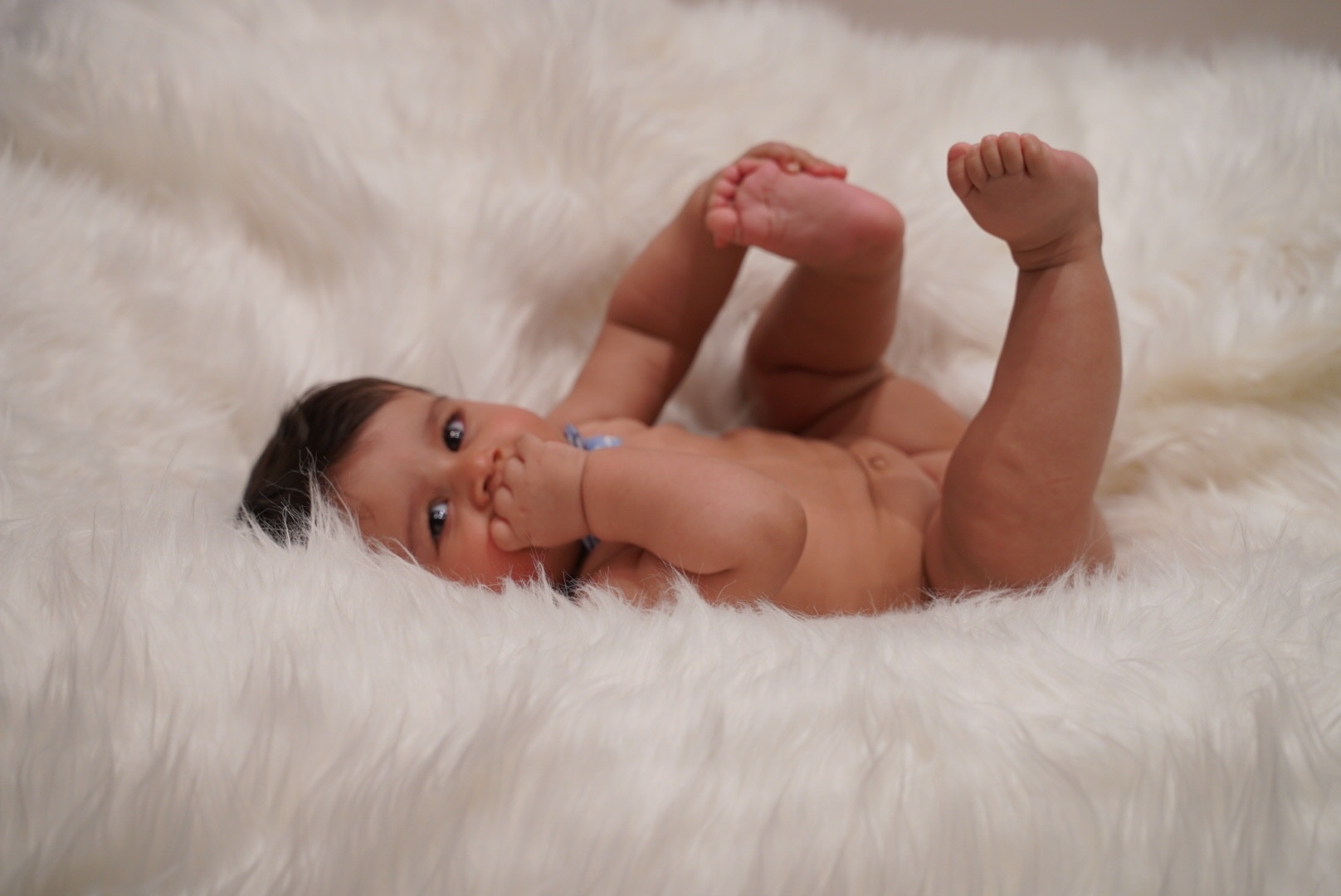 Baby lying playfully on a soft white studio blanket