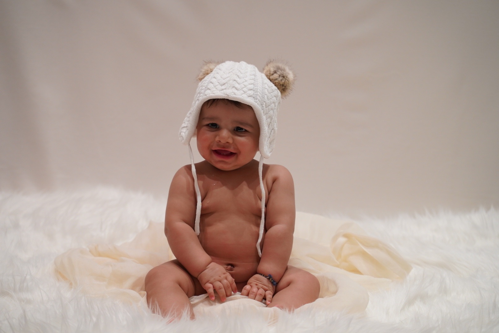 Smiling baby wearing a knitted hat in the studio
