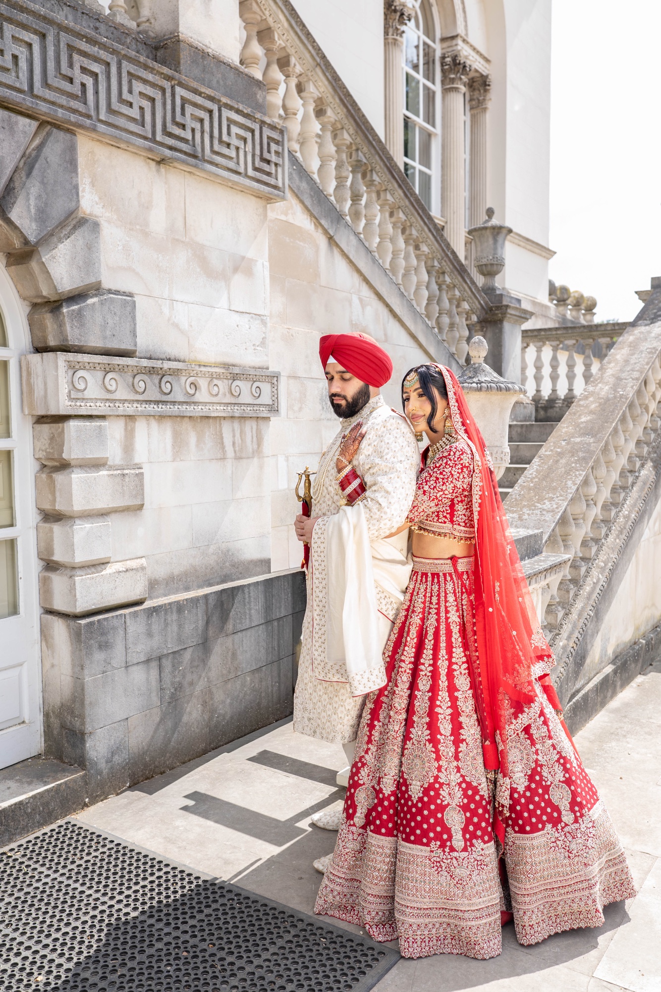 Sikh bride and groom embracing beside a grand stone staircase