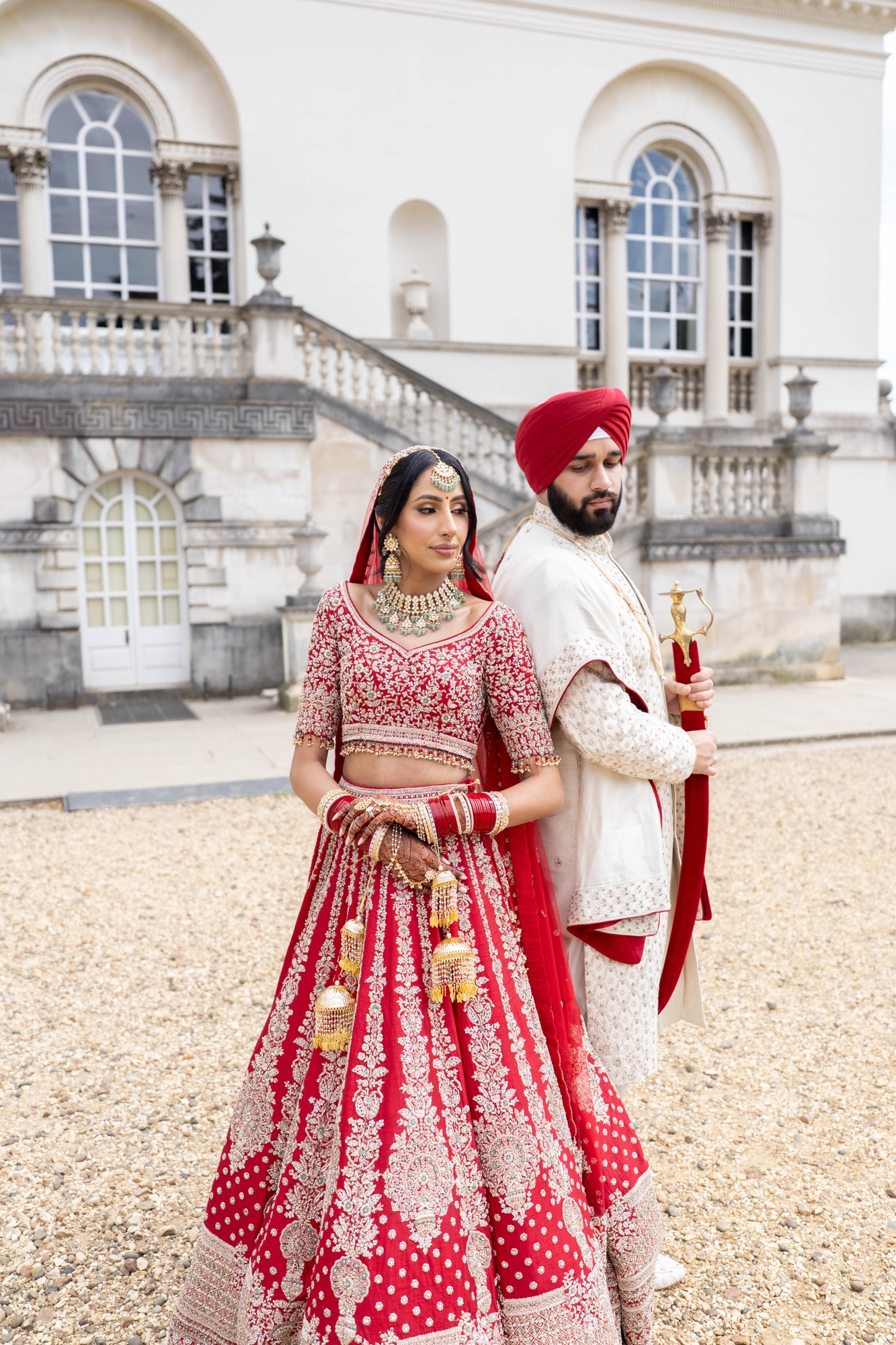 Sikh bride and groom posing back to back outside their wedding venue