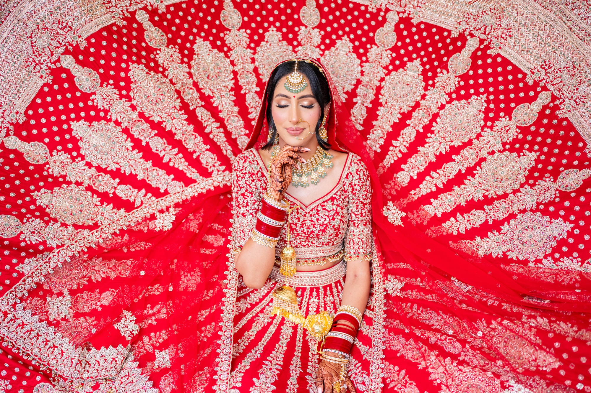 Bride framed by the intricate red and gold embroidery of her wedding dress